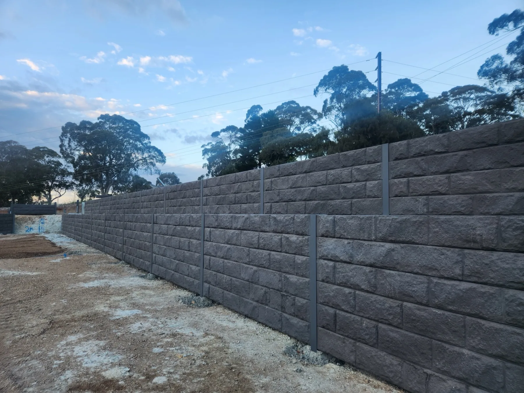 Wide engineered retaining wall on a steep Adelaide block at dawn